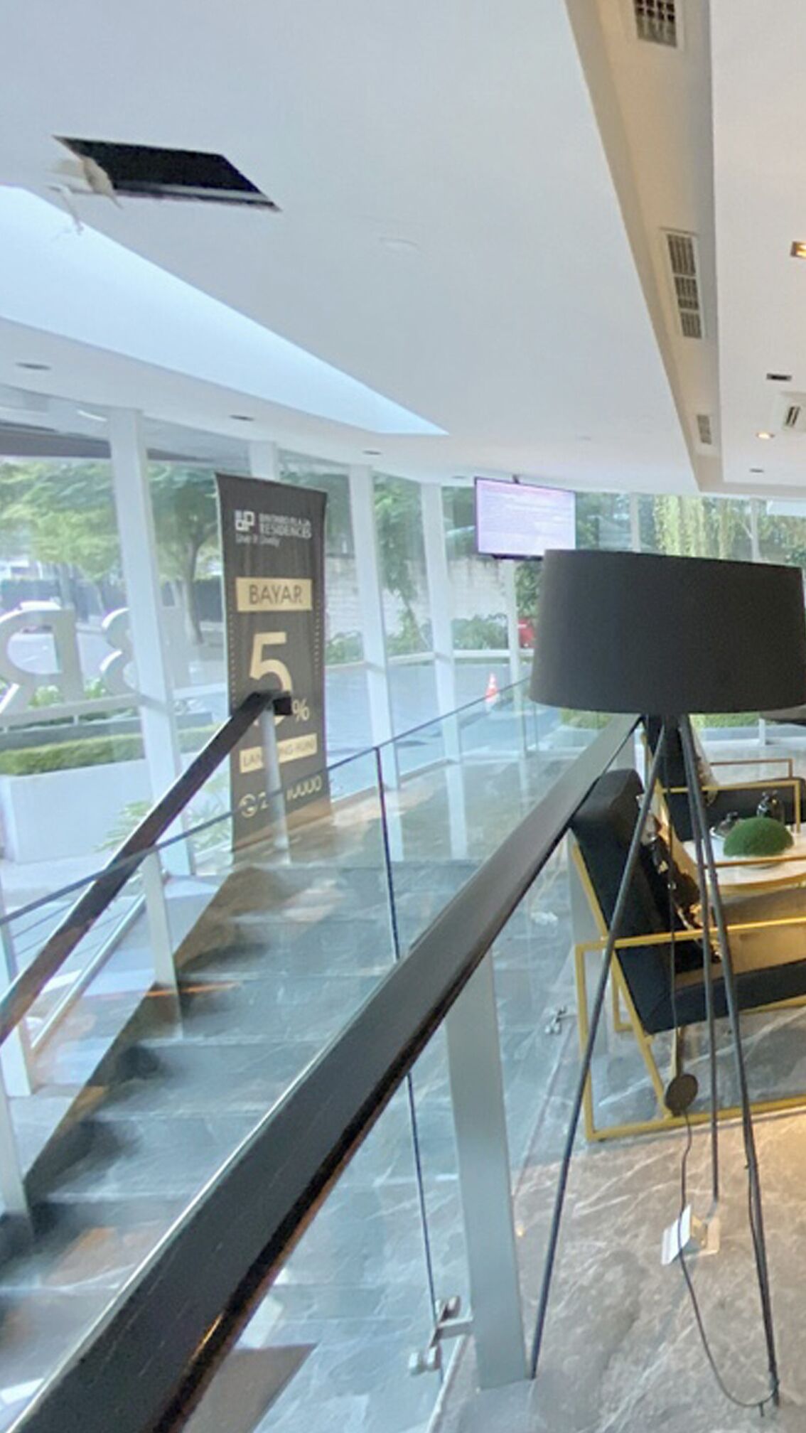 A modern interior with a glass railing, a digital screen, and a sign indicating a 5% discount.