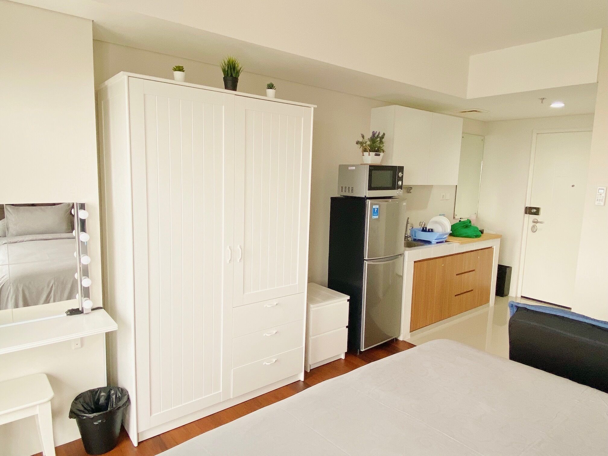 Une chambre compacte comprenant un lit, une armoire, une petite kitchenette équipée d’un four à micro-ondes et une poubelle.