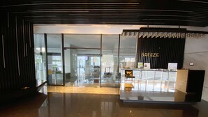 A modern hotel lobby with a reception desk labeled "BREEZE" and a glass entrance. - Breeze Apartments at Bintaro by OkeStay (South Tangerang)