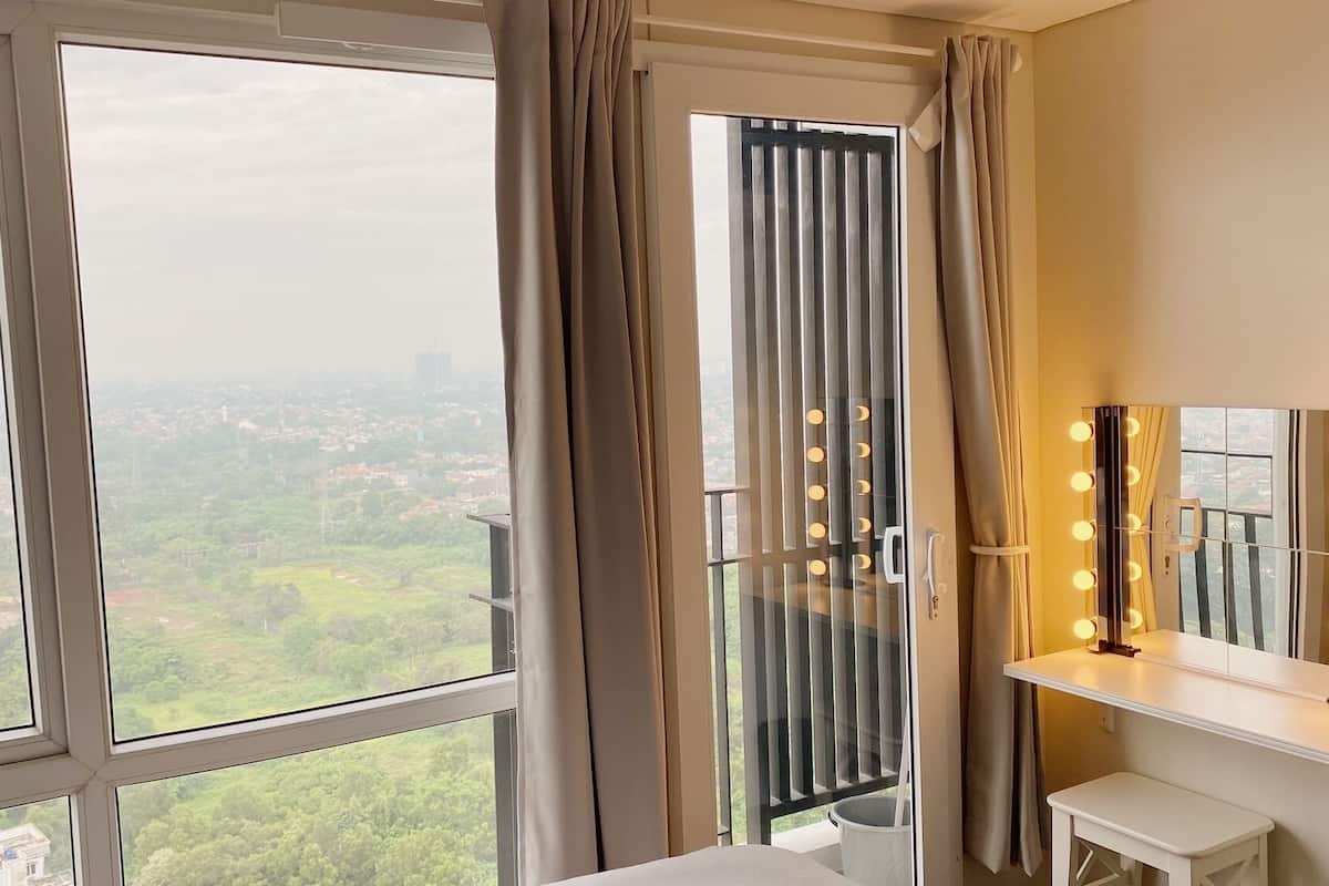 A room with large windows, a vanity with lights, and a view of a cityscape.