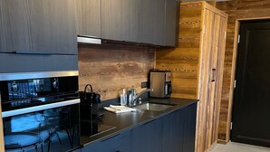 Una cocina moderna con gabinetes oscuros, un horno de acero inoxidable y un microondas integrado.