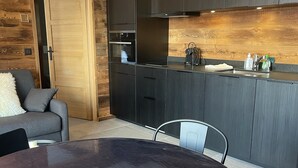 Una cocina moderna con armarios oscuros, horno empotrado y pileta de acero inoxidable.