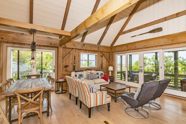 Ein geräumiger Raum mit Holzboden, einem Esstisch mit Stühlen, einer Couch und einem Massagesessel.