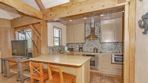 Una cocina moderna con vigas de madera, una isla grande y un respaldo de piedra.