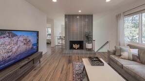 Una sala de estar moderna con un televisor de pantalla plana grande, una chimenea, un sofá y una mesa de centro.