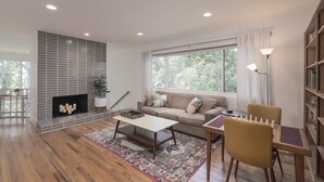 Una sala de estar moderna con chimenea, un sofá, una mesa de centro, una mesa de ajedrez y una estantería.