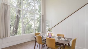 Comedor con un ventanal grande, suelo de madera y una mesa dispuesta para cuatro.
