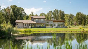 Ein modernes Haus mit großem Teich, umgeben von Bäumen.