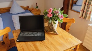 A laptop on a wooden table with a flower vase in the background. - Ferienhof Hofer (Absberg)