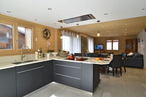 A modern kitchen with dark cabinets, a large island, and a dining area with a sofa and chairs. - 170m² apartment for 8 people in village centre - Chatel Reservation (Châtel)