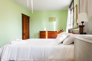 Ein Schlafzimmer mit einem Bett, einem Schminktisch, einer Lampe und einer Tür.
