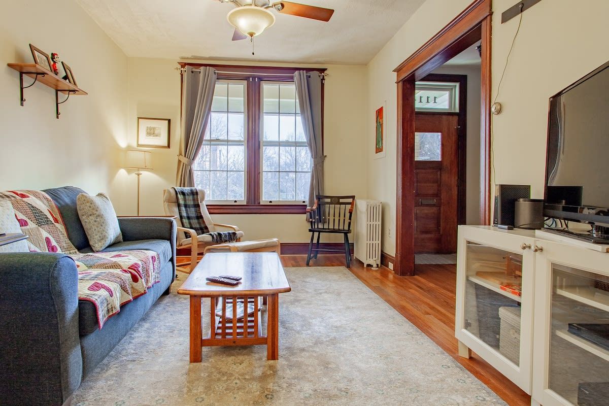 A cozy living room with a sofa, a wooden coffee table, and a television on a cabinet.
