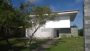 Une maison moderne avec un toit plat, un mur en pierre et un chemin pavé menant à l’entrée.