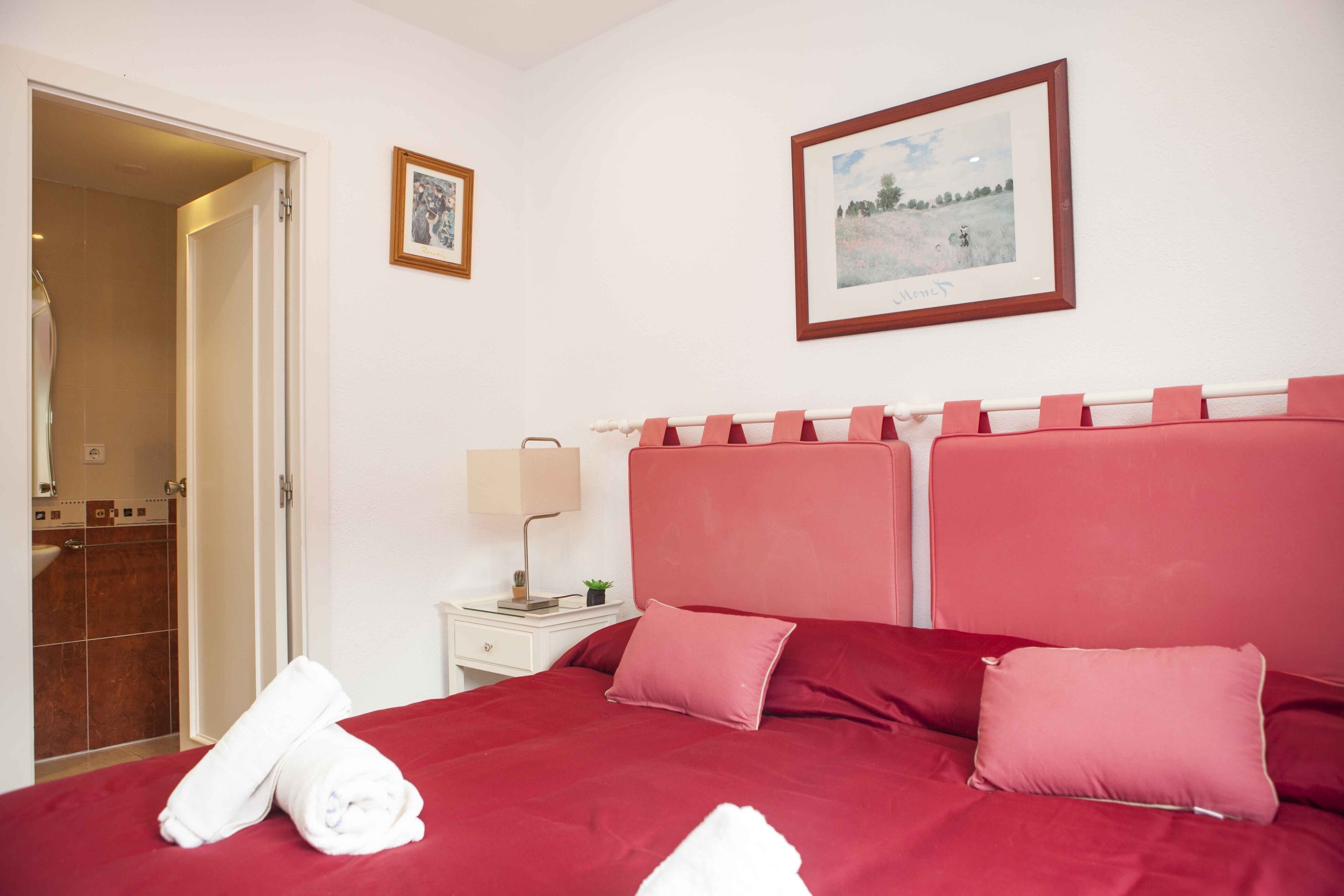 A hotel room with a large bed, a nightstand, a lamp, and a framed picture on the wall.