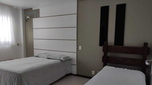 Un dormitorio con dos camas individuales, un espejo grande y un interruptor de luz en la pared.