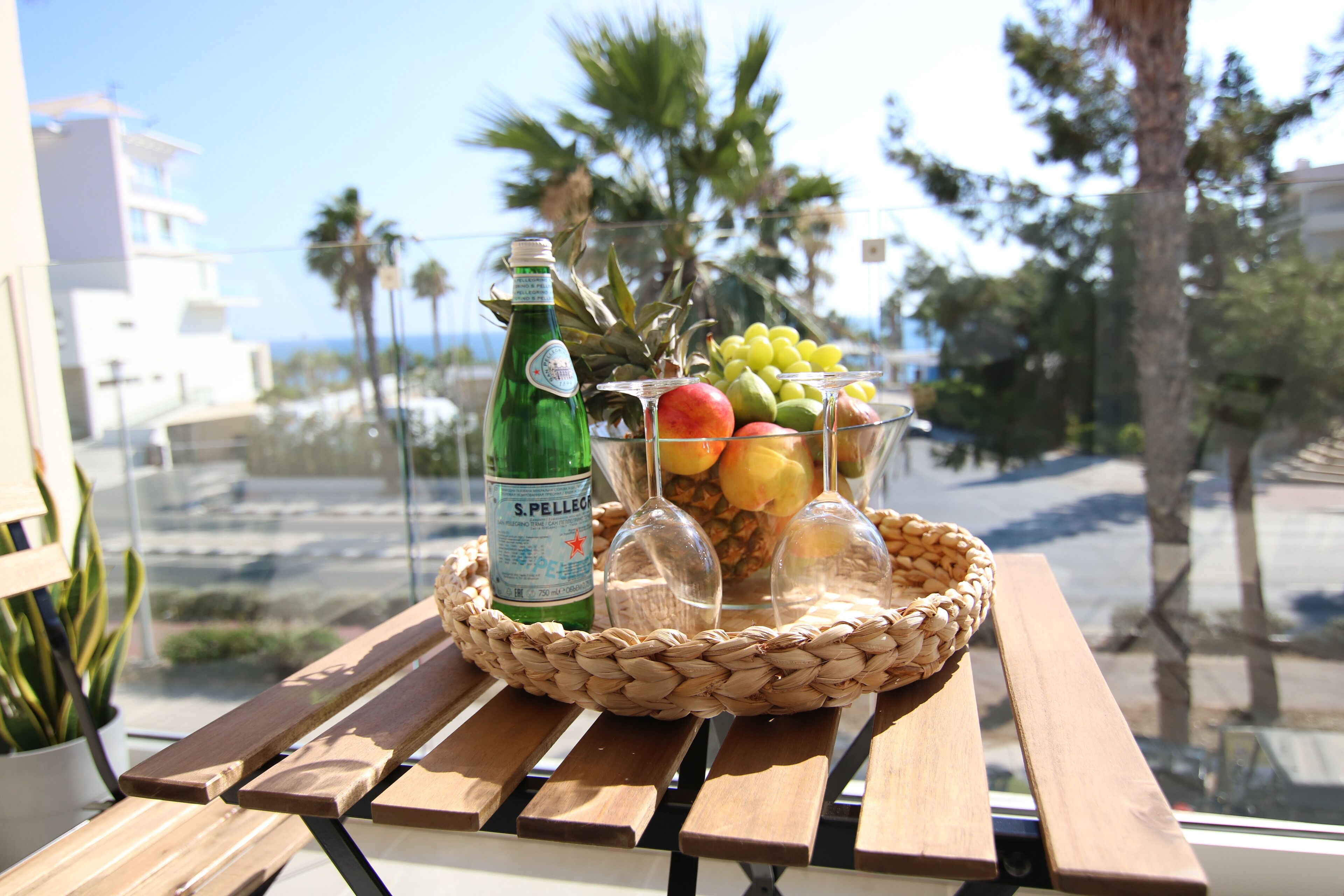 A table with a bottle of S. Pellegrino water, a fruit bowl, and two wine glasses.