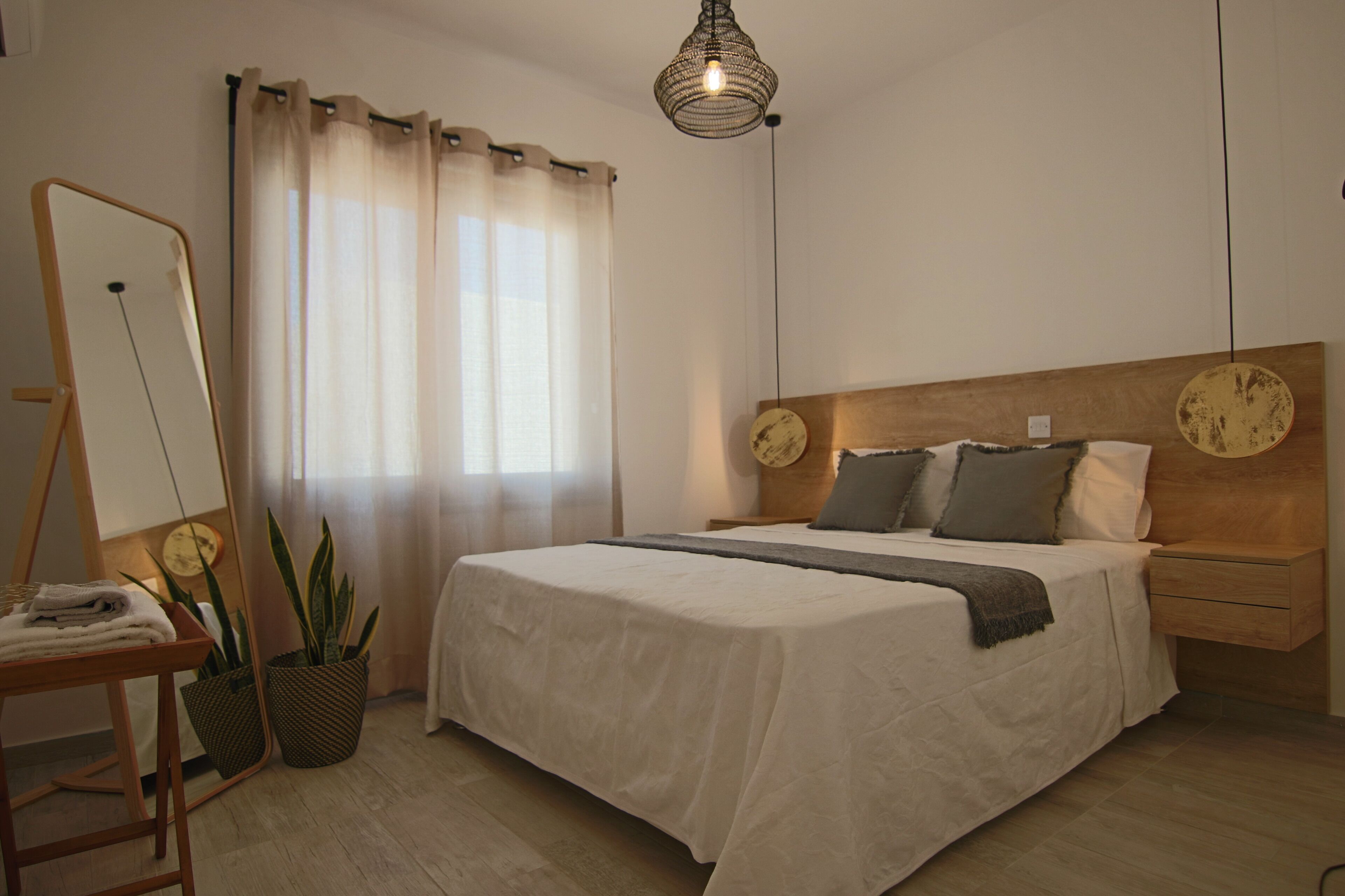 Una camera da letto con un letto, comodini, uno specchio, un lampadario e una finestra con tende.
