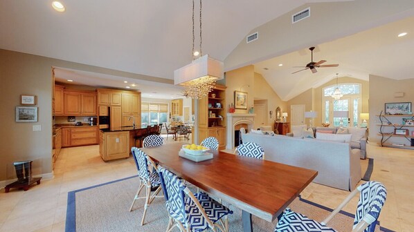 A spacious living area with a wooden dining table, patterned chairs, and a large island with seating. - Nicely Appointed Home with Lagoon Views! (Hilton Head)