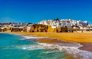 A coastal town with white buildings on a hillside overlooking the beach.