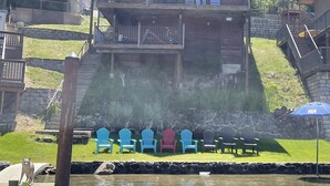A wooden lodge with multiple balconies, a stone wall, and a dock with chairs.