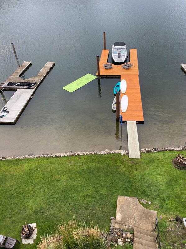A dock with a boat, a wooden pier, and a grassy area with a fire pit. - Lakefront Cabin in Carey Bay (Worley)