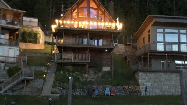 A lodge with a prominent wooden structure, a dock with boats, and a surrounding forest.