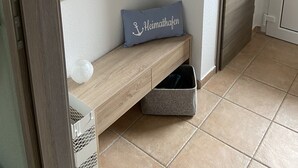 Een hal met een houten bankje, een wandplank en een deur.
