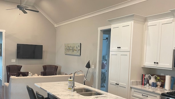 Une cuisine moderne dotée d’un grand îlot central, de tabourets de bar, d’un four encastré et d’un ventilateur de plafond.