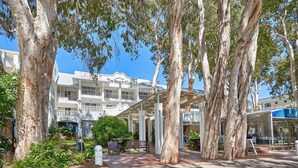 The Beach Club with a covered outdoor seating area, surrounded by large trees and a well-maintained garden.