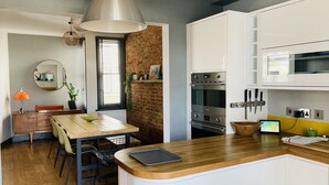 Uma cozinha moderna com armários brancos, bancada de madeira e forno embutido.