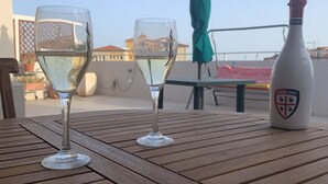 Zwei Weingläser auf einem Holztisch mit einer Flasche Cagliari-Wein.