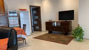 Ein Wohnzimmer mit Sofa, Fernseher, Schrank, Teppich und einer Tür zu einem anderen Raum.