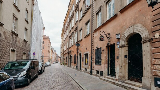 A cobblestone street lined with historic buildings, some with visible signage and architectural details. - ShortStayPoland Piwna B25 (Warsaw)
