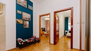 A hallway with a wooden herringbone floor, a bench with floral upholstery, and a wall adorned with framed photographs. - ShortStayPoland Piwna B25 (Warsaw)