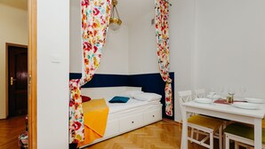 A bedroom with a bed, a table with chairs, and a window with curtains. - ShortStayPoland Piwna B25 (Warsaw)