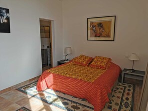 A bedroom with a bed, two bedside tables, a nightstand, a painting, and a patterned rug.
