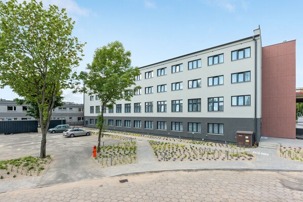 A modern building with multiple windows and a parking area with trees and plants. - Apartgdynia (Gdynia)