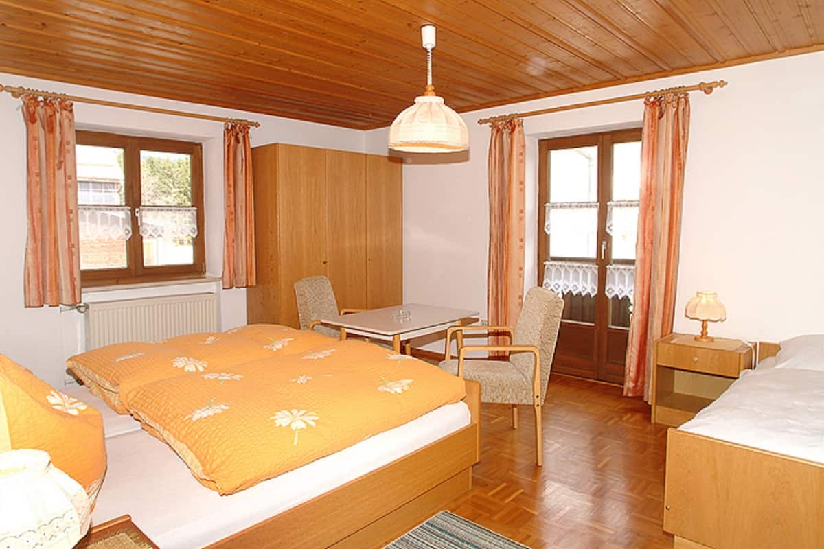 Ein Zimmer mit Bett, Tisch, Stuhl, Lampe und Fenster.
