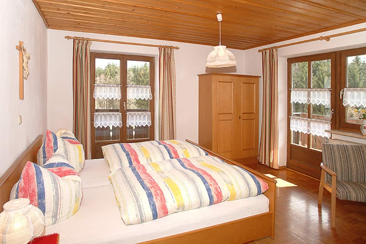 Ein Schlafzimmer mit einem hölzernen Bett, einem Kleiderschrank und einem Fenster mit Vorhängen.