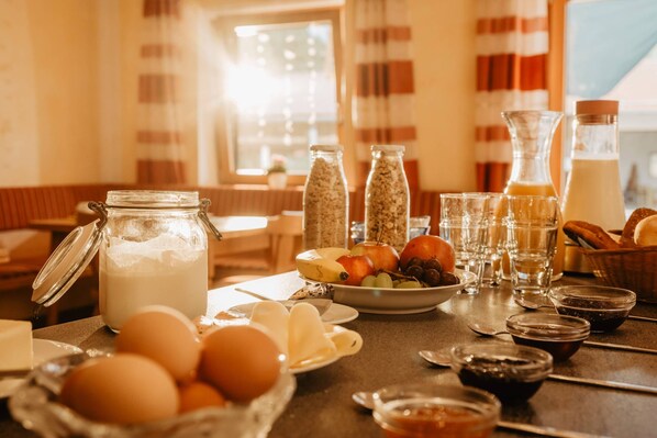 A breakfast setting with eggs, fruits, and beverages on a table.