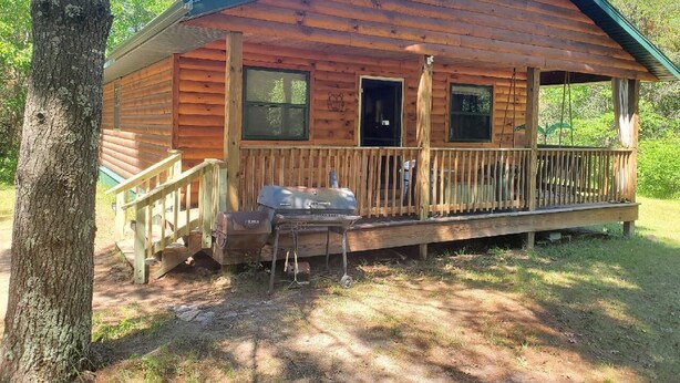 A wooden cabin with a porch, a grill, and a door. - Private cabin with direct ATV/UTV trail access (Fairchild)