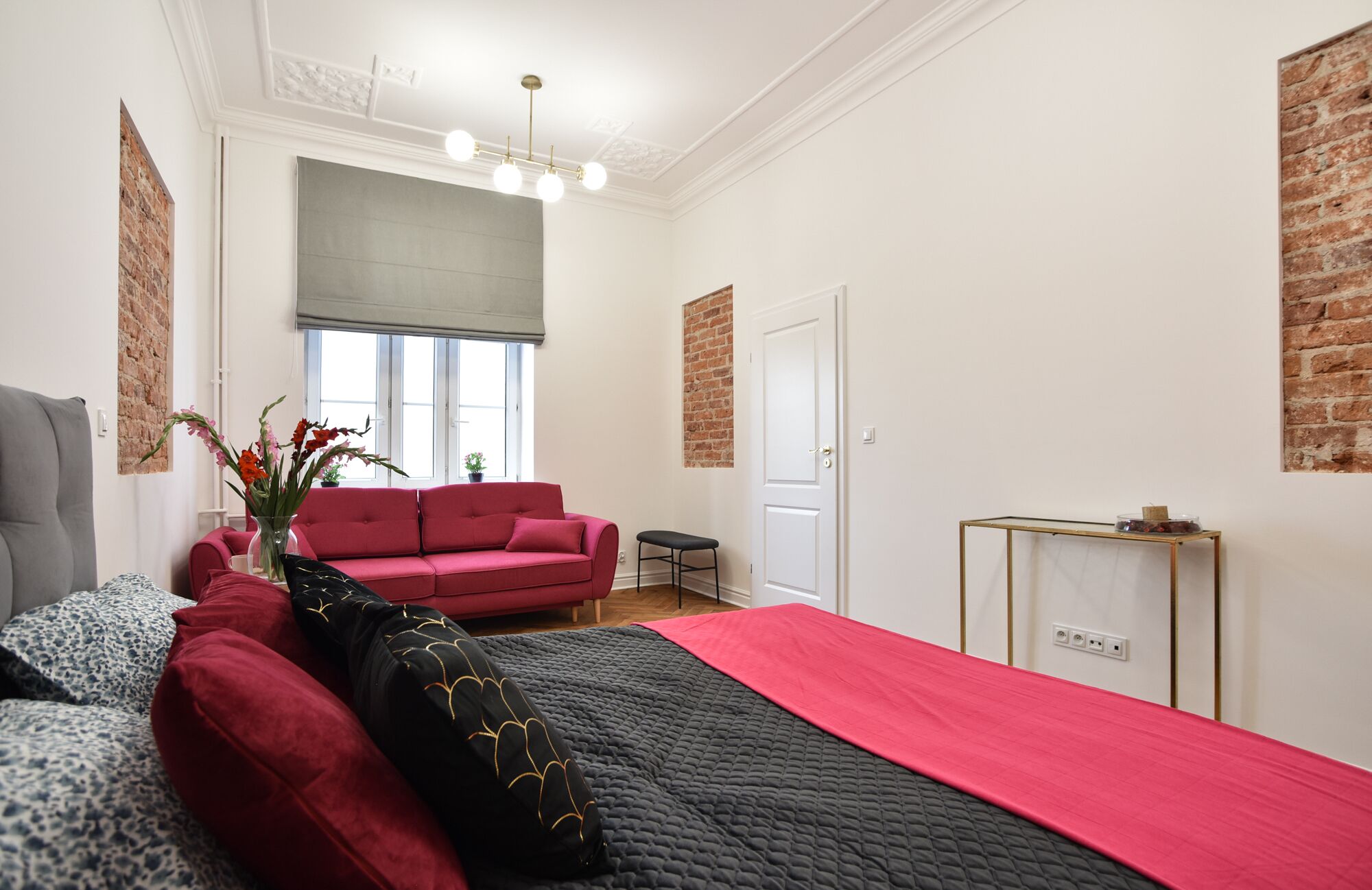 Una camera da letto moderna con un letto grande, un divano rosso, un tavolino e una finestra con vista.
