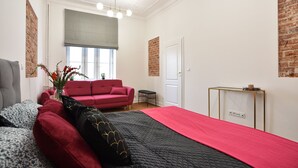 Una camera da letto moderna con un letto grande, un divano rosso, un tavolino e una finestra con vista.