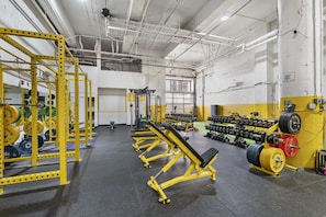 A gym with weightlifting equipment, benches, and dumbbells.