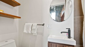 Een badkamer met een toilet, een wastafel met spiegel en een handdoekhouder.