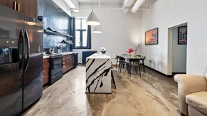 A modern kitchen with stainless steel appliances, a marble island, and a dining area with a table and chairs. - Spacious Loft 2 bedroom in N Oakland 400, sleeps 8 (Pittsburgh)