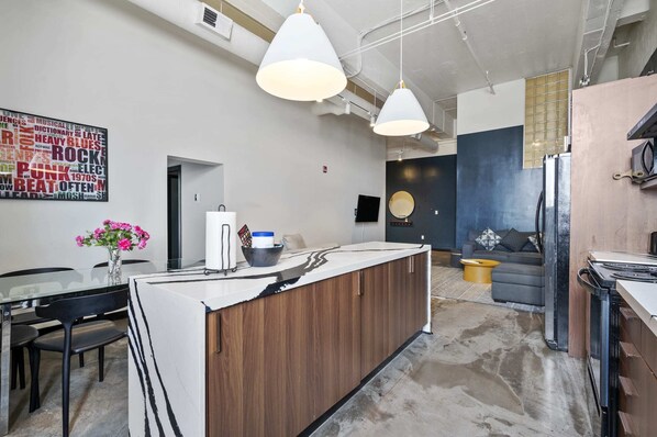 A modern kitchen with a central island, pendant lighting, and a word cloud mural on the wall. - Spacious Loft 2 bedroom in N Oakland 400, sleeps 8 (Pittsburgh)