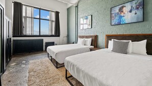 A hotel room with two beds, a large window with curtains, a radiator, and artwork on the walls. - Spacious Loft 2 bedroom in N Oakland 400, sleeps 8 (Pittsburgh)
