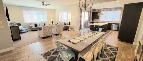 A spacious living area with a dining table, sofas, and a kitchen in the background.