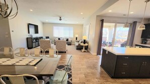 A spacious living area with a dining table, chairs, a sofa, and a kitchen area with a large island. - Fully Equipped Vacation Home in Paradise Village (Santa Clara)